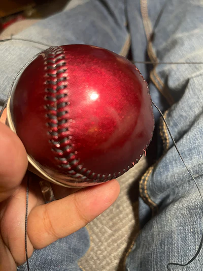 Red baseball being hand stitched
